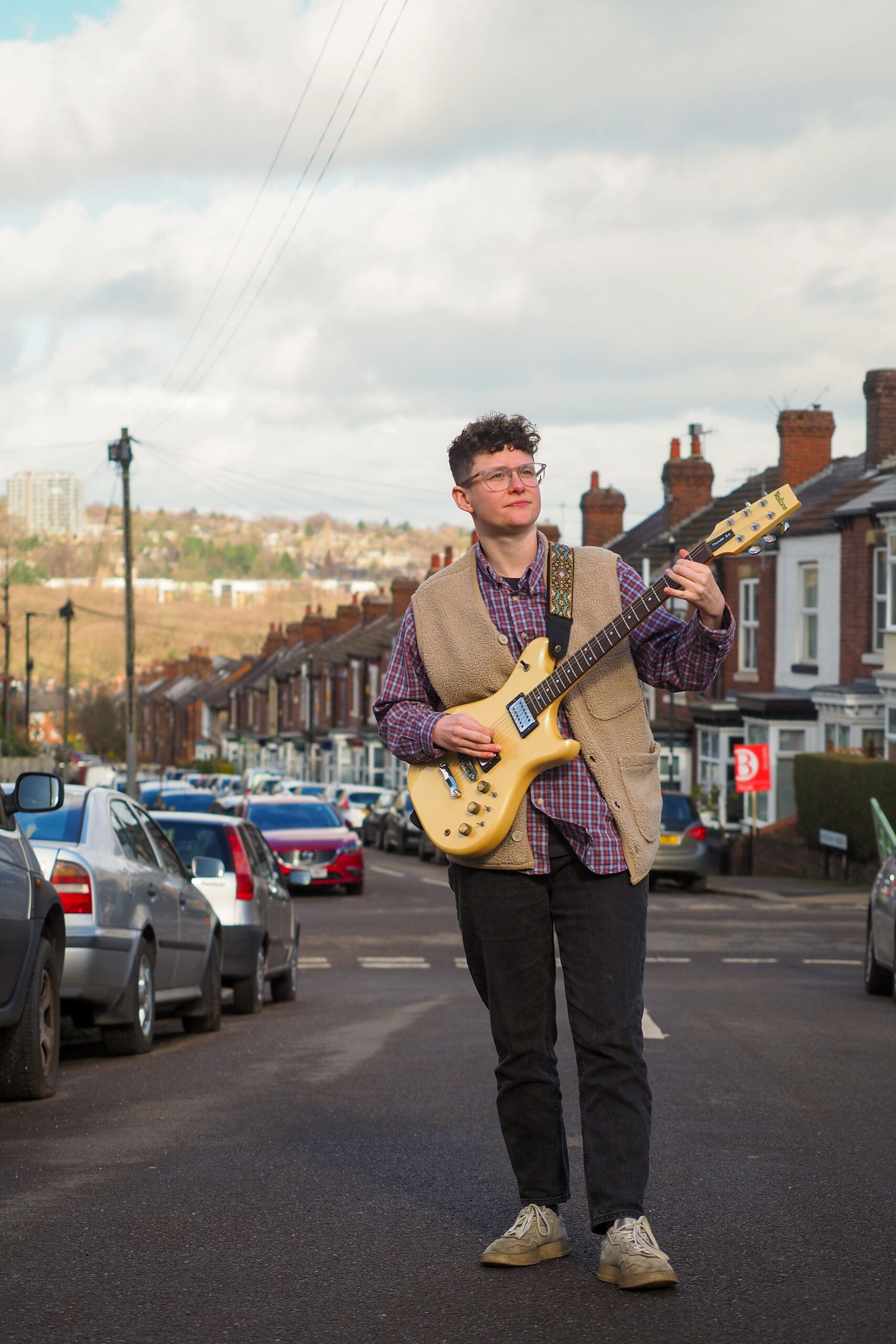 Annie Priest playing guitar walking up a Sheffield street