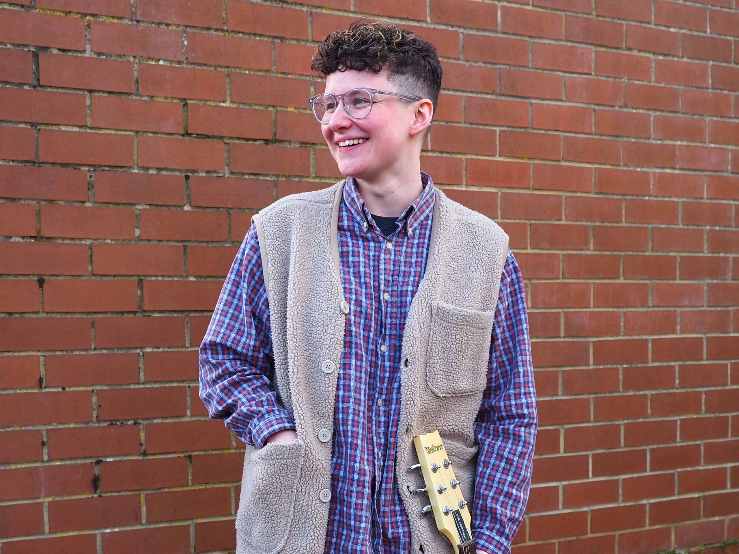 Annie Priest against a red brick wall
